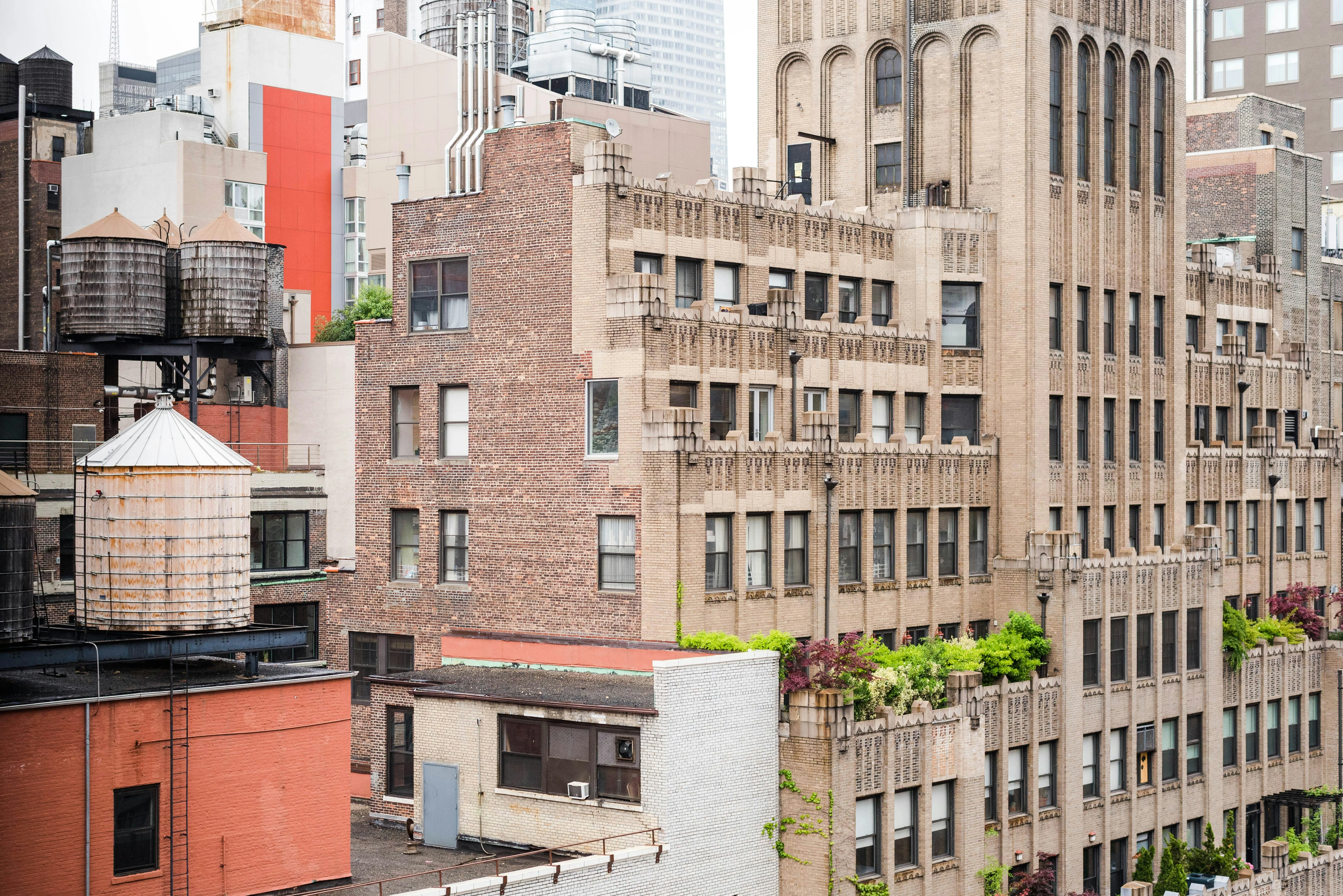 Rooftop view of NYC buildings with water towers, brick facades, and Art Deco architectural details.